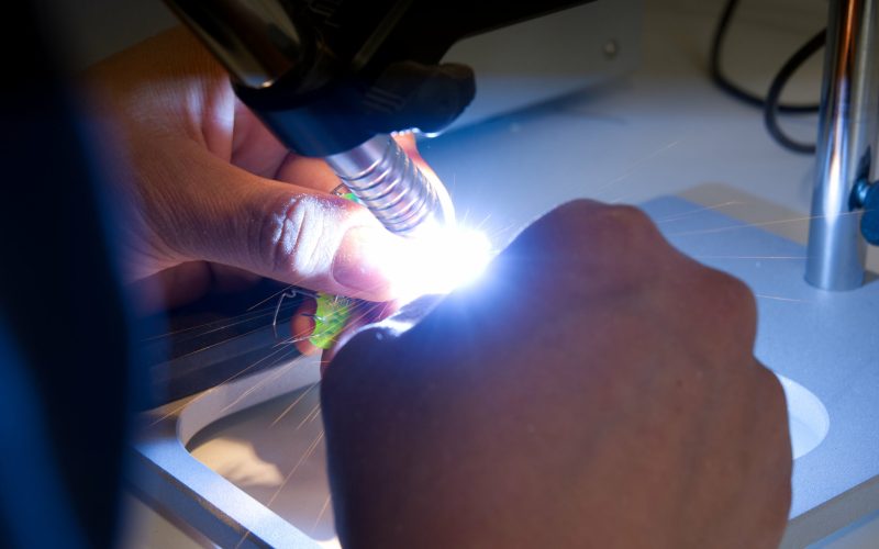 Im Dentallabor schweißt ein Zahntechniker mit Laser eine filigrane KFO-Apparatur.