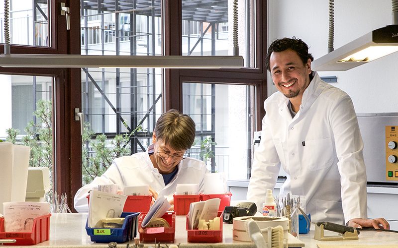 Zwei Labor-Mitarbeiter, einer arbeitet am Modell, der andere beobachtet – präzise Teamarbeit.